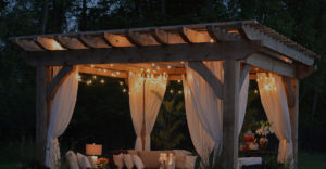 pergola in a yard at night with white lights dangling