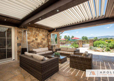 Apollo louvers integrated into exsisting wood frame and roof over an outdoor seating area featuring wicker furniture.