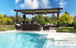 Three bay freestanding louvered pergola featuring corbels with integrated fans installed next to pool.