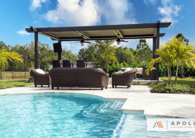 Three bay freestanding louvered pergola featuring corbels with integrated fans installed next to pool.