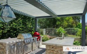 Freestanding smart pergola featuring outdoor kitchen with gas and charcoal BBQs, counterspace, & sink.
