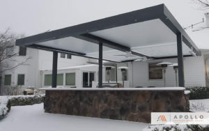 Cantilivered louvered pergola with integrated heaters and fans, half open, half closed on snowy day.