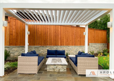 Freestanding adjustable pergola in white covering outdoor entertainment area.