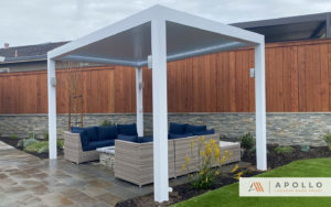 Freestanding all-white louvered roof over a small backyard seating area, providing shade and comfort for outdoor relaxation.
