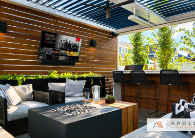 Louvered roof with dark louvers/light frame over an entertainment area with a wood panel wall for added privacy & shelter.