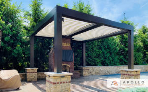 Custom frame configuration of this louvered pergola wraps around fireplace and features custom stonework at post bases.