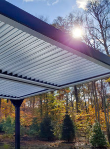 Photo of a two bay Apollo louvered roof with beautiful fall colors and sun shining through the trees.