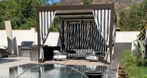 Personalized pergola design featuring striped curtains stands poolside creating unique outdoor space.