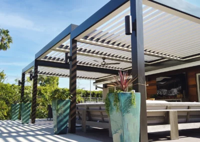 Energy-efficient wall attached multi-tier louvered pergola over an outdoor entertainment area.