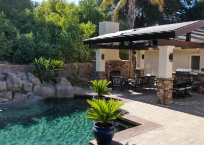 Luxury outdoor living space featuring poolside modern louvered pergola. Louvers integrated into custom pitched roof.