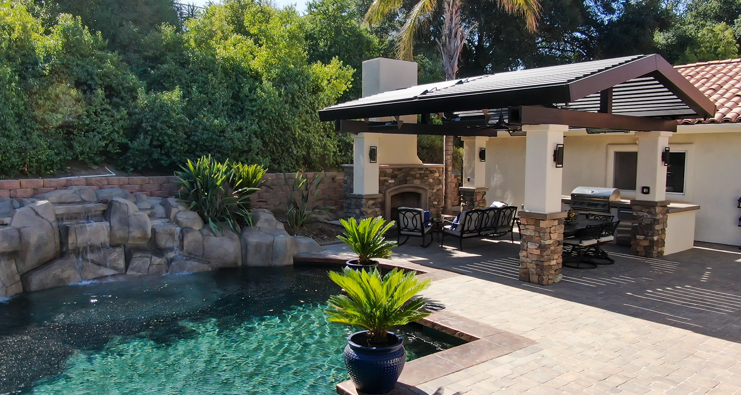 Luxury outdoor living space featuring poolside modern louvered pergola. Louvers integrated into custom pitched roof.