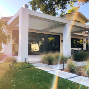 Louvered roof system integrated into a custom home extension with large windows and matching architecture.