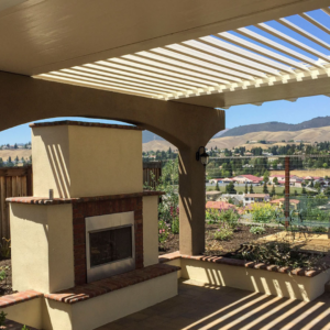 Louvered roof integrated into a custom patio cover design with an insulated section, fireplace, and outdoor seating area.