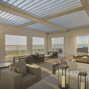 White louvered roof integrated into a steel structure overlooking the ocean in a hospitality setting.