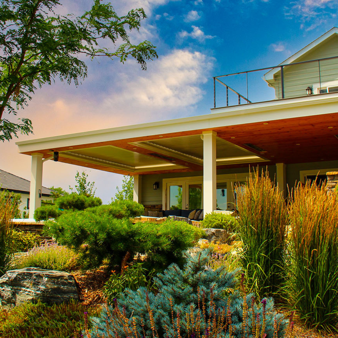 Integrated louvered roof bays with wood paneling on a two-story residential home surrounded by local landscaping.