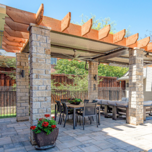 Apollo louvered roof integrated into custom wood framing with corbels atop stone columns, showcasing a rustic look.