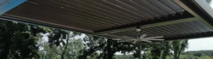 Bronze louvered pergola with steel fan and recessed lighting.