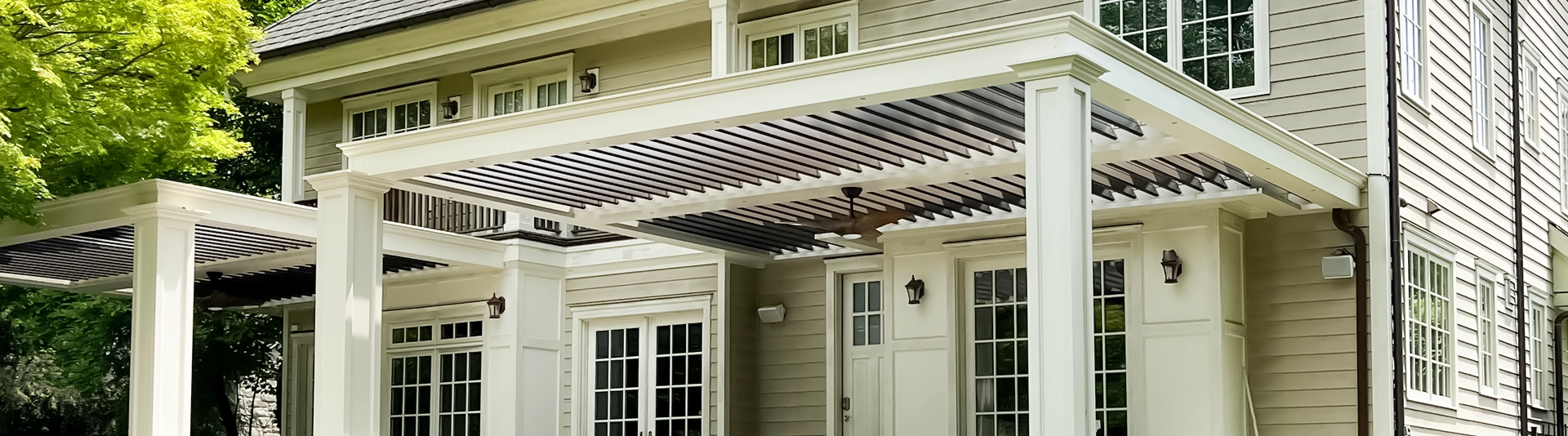 Front view of wall-attached multi-bay aluminum pergolas to a multi-story home.