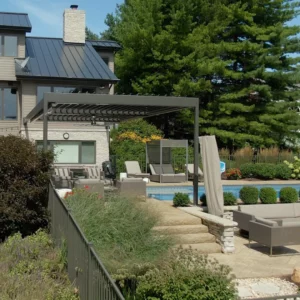 Contemporary home with rustic stone elements, featuring a modern louvered pergola overlooking a pool.