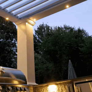 White Apollo louvered pergola with built-in recessed lights over a BBQ area, demonstrating louvers opening and closing.