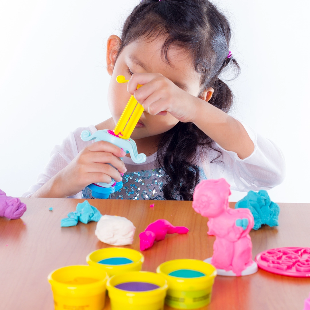 Child using a playdough press to create shapes, illustrating the concept of extrusion.