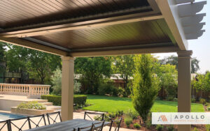 Stylish Apollo motorized pergola over an elegant patio in a lush garden setting.