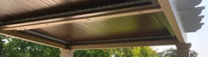 Elegant bronze louvered pergola with integrated lighting in a garden setting.