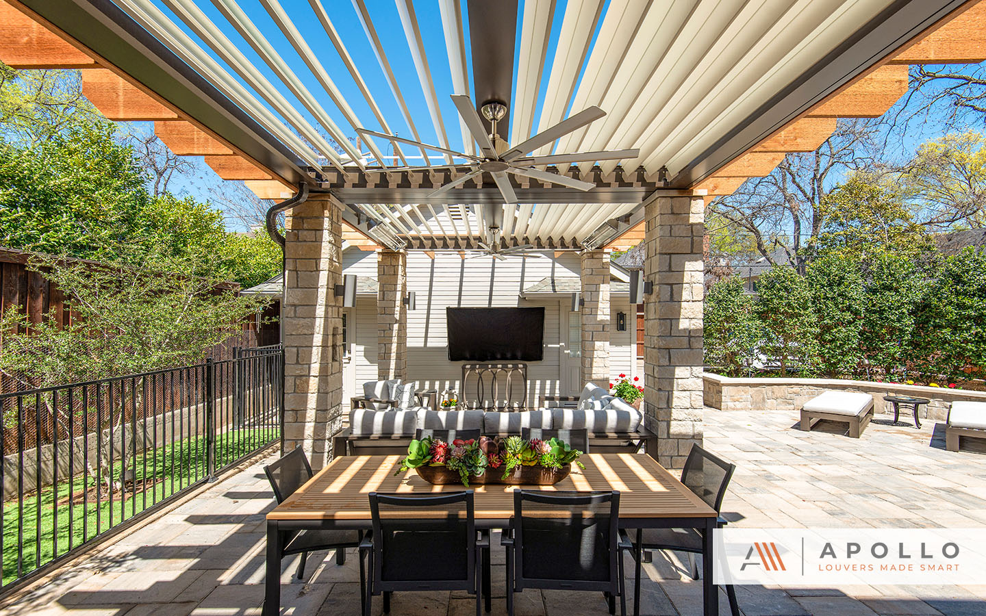 Apollo louvered pergola over an outdoor seating area with dappled lighting, enhancing the cozy ambience.