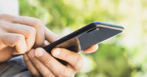 Close-up of hands holding a smartphone with a home automation app to control a smart pergola's settings.