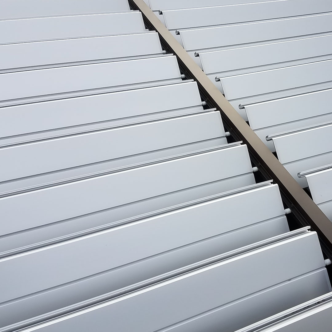 Close-up view of a smart pergola's sleek aluminum louvers partially open to regulate sunlight and air flow