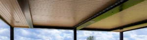 Motorized louvered pergola with adjustable louvers closed, showcasing sleek design and integrated lighting against a blue sky background.