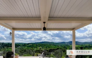 Louvered roof pergola with a panoramic view of lush green hills and cloudy skies.