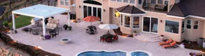 A custom louvered pergola installed on a patio with a pool and hot tub.