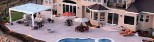 A custom louvered pergola installed on a patio with a pool and hot tub.