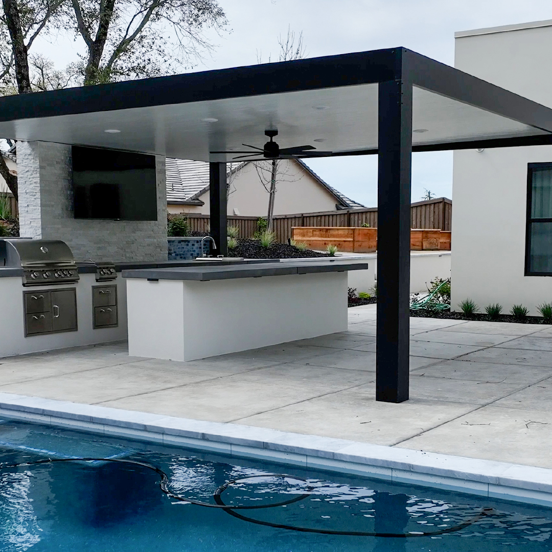 Modern covered outdoor kitchen and bar beside blue swimming pool