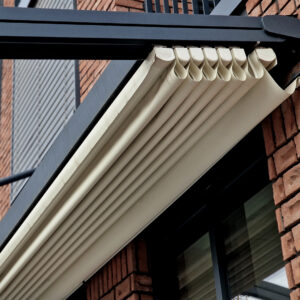 Folded retractable pergola roof with cream fabric on metal frame