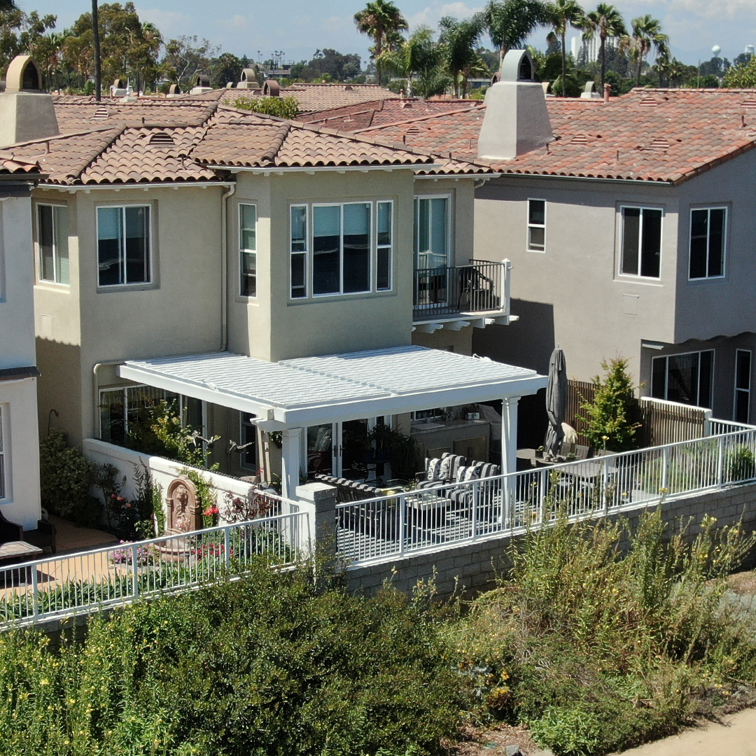 Coastal Home with Louvered Patio Cover Two-story coastal home with white louvered patio cover in backyard