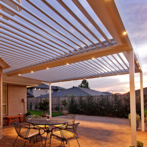Backyard patio with louvered roof and built-in LED lighting at sunset
