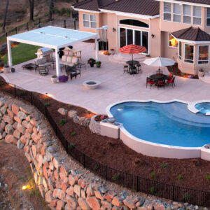 elevated backyard view with patio cover pool seating and stone retaining wall