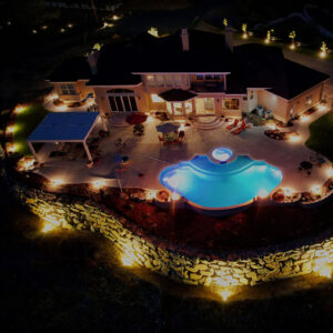 night aerial view of luxury patio with pool cover and glowing landscape lights
