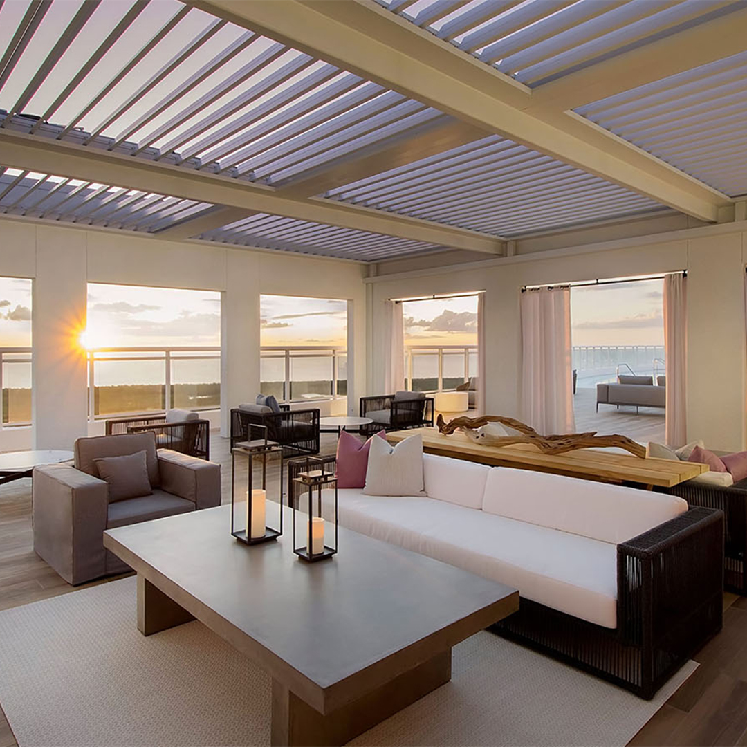Luxury outdoor lounge beneath a louvered pergola with sunset views