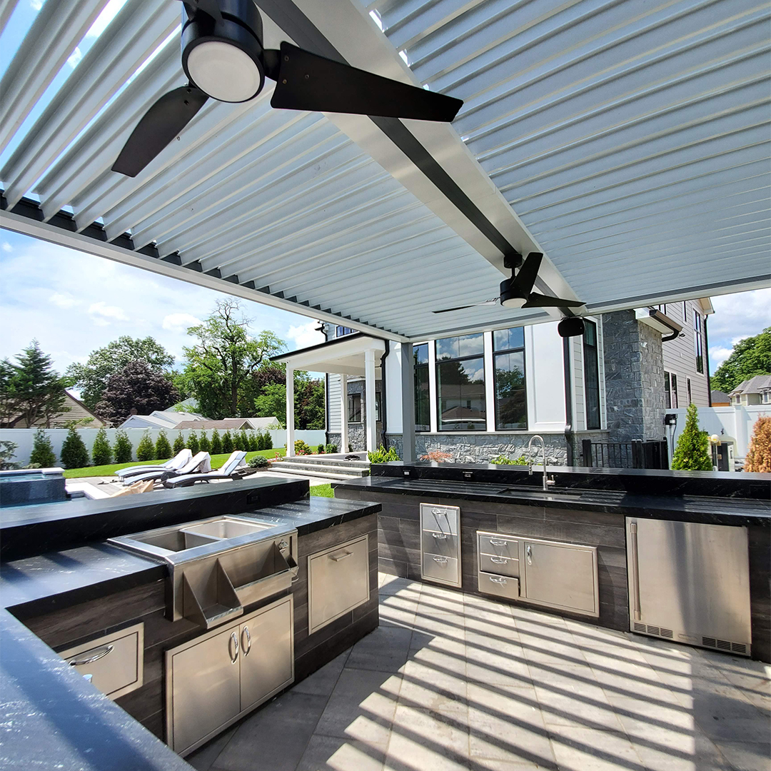 Luxury outdoor kitchen beneath a louvered pergola with ceiling fans