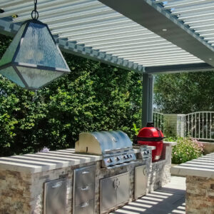 Outdoor kitchen with grill under freestanding louvered pergola in Laguna Niguel