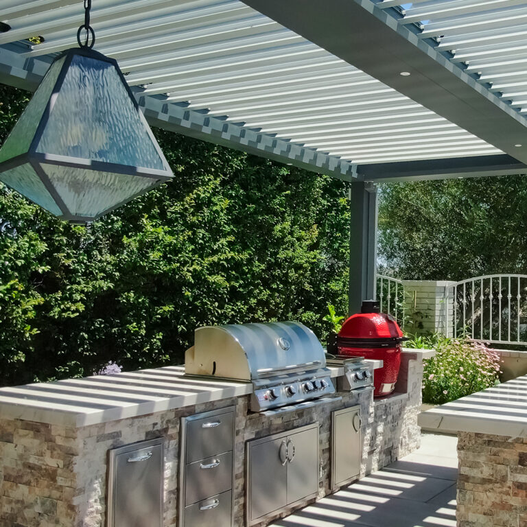 Outdoor kitchen with grill under freestanding louvered pergola in Laguna Niguel