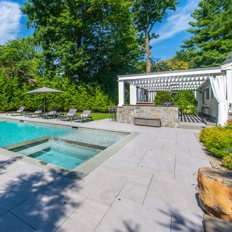 Wide backyard view with pool, spa, loungers, and white pergola in Tenafly NJ