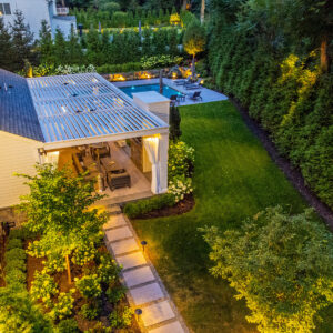 Aerial evening view of white louvered pergola, pool, and landscaped backyard in Tenafly NJ