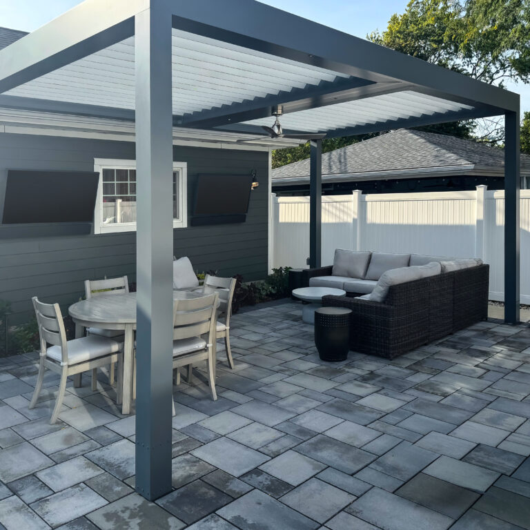 Gray aluminum louvered pergola with open louvers, a ceiling fan, and outdoor TV over a patio with dining and lounge seating