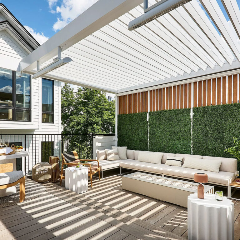 Open louvers cast striped shadows over a rooftop patio with a sectional sofa, fire pit, and slatted wood privacy wall