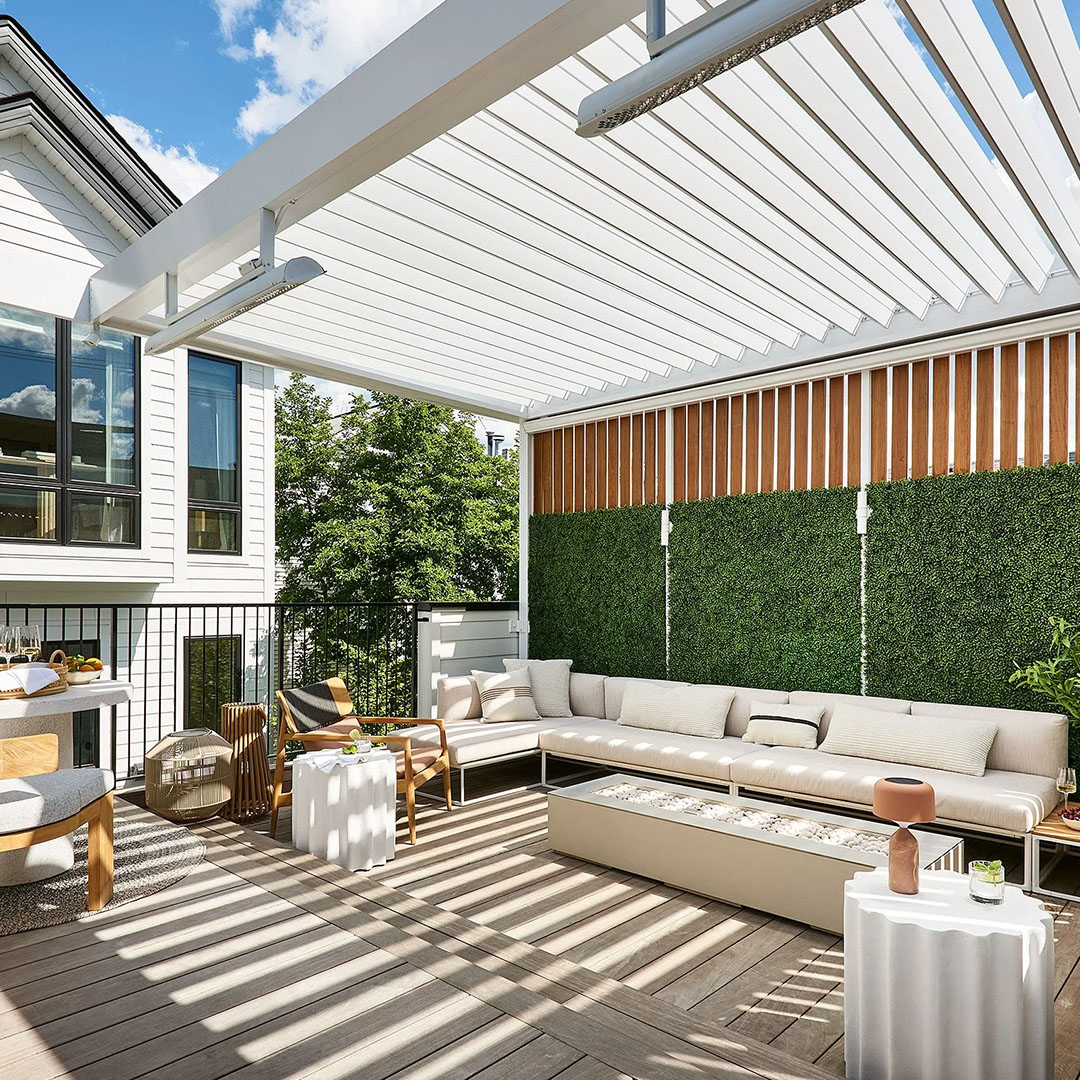 Open louvers cast striped shadows over a rooftop patio with a sectional sofa, fire pit, and slatted wood privacy wall
