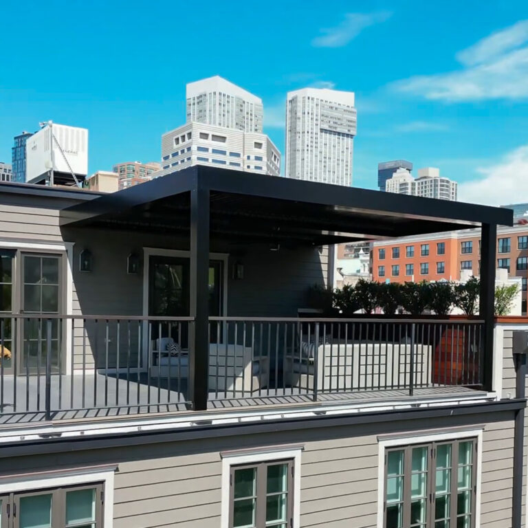 Dark charcoal aluminum louvered pergola with closed louvers on a rooftop deck with seating, surrounded by a city skyline